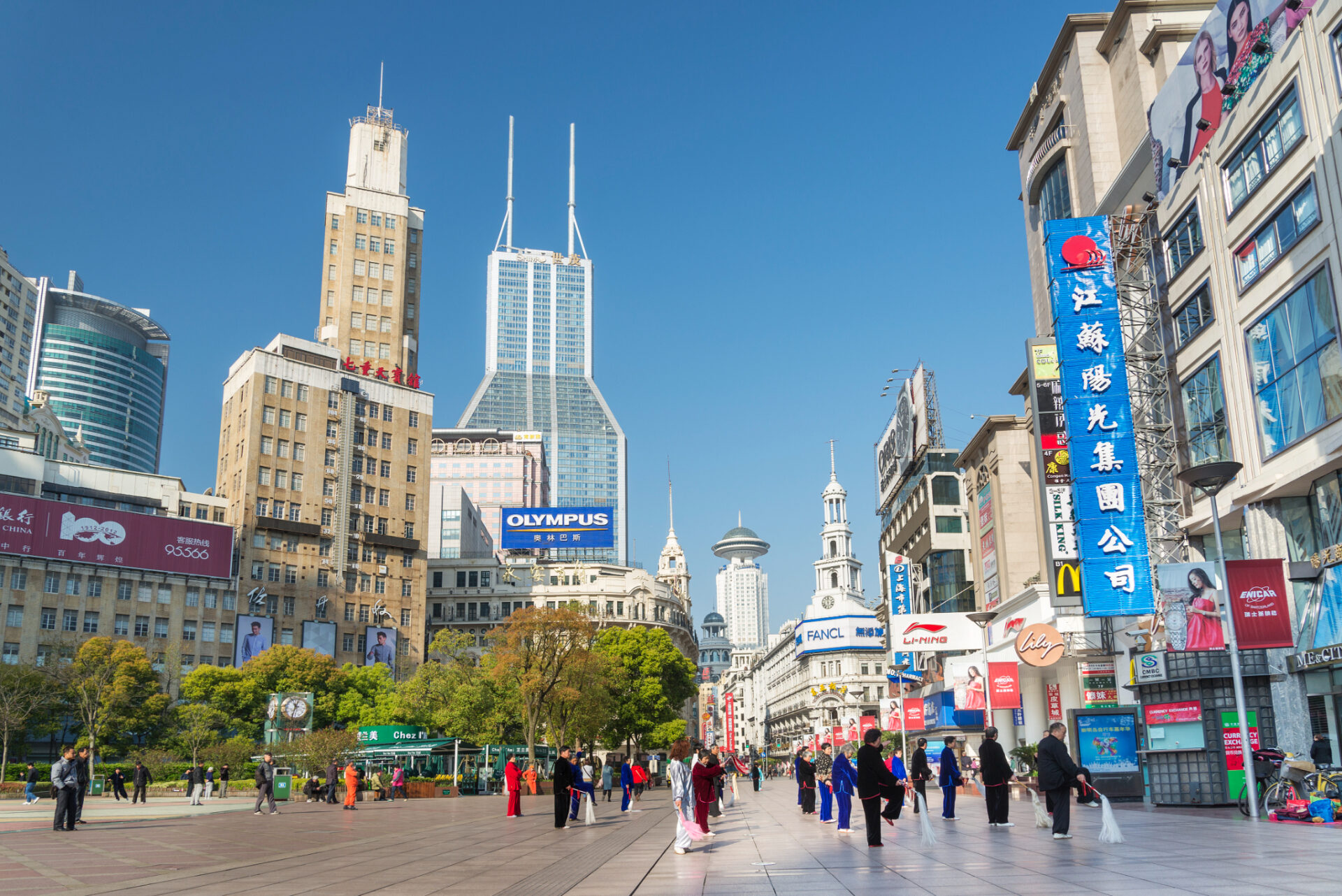 Belebte Einkaufsstraße Nanjing Road in Shanghai mit Geschäften, Werbetafeln und Fußgängerbereich.